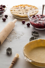 An unbaked pie shell with fresh cherry pie filling in behind. 
