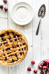Top down view of a freshly baked lattice cherry pie with plates for serving.