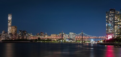 Illuminated Queensborough bridge with a background of Manhattan cityscape at night