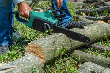 Cord Chainsaw. Close-up of woodcutter sawing chain saw in motion, sawdust fly to sides. Chainsaw in motion. Hard wood working in forest. Sawdust fly around. Firewood processing.