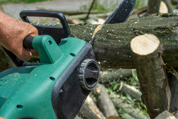 Cord Chainsaw. Close-up of woodcutter sawing chain saw in motion, sawdust fly to sides. Chainsaw in motion. Hard wood working in forest. Sawdust fly around. Firewood processing.