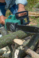 A man is sawing a tree with a chainsaw. A young near his house