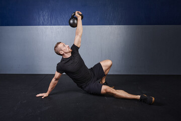 man performs a kettlebell Turkish get up - obrazy, fototapety, plakaty