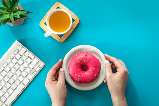 Donut, tea and keyboard on a blue background, flat lay.