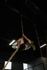 woman climbs rope in gym