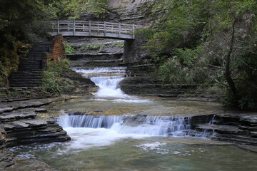 Fototapeta na wymiar waterfall in the mountains. bridge over river. double waterfall in brook in gorge.