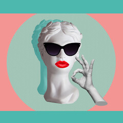 Confident antique female statue's head in black sunglasses with red lips shows the ok gesture with...