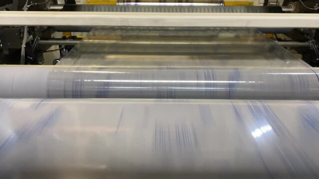 High speed flexographic printing. Printed film passes through the rollers in a flexo press and is rewound.