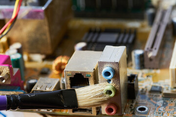 Brush cleaning an old computer board from dust and dirt. Close-up.