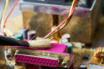Brush cleaning an old computer board from dust and dirt. Close-up.