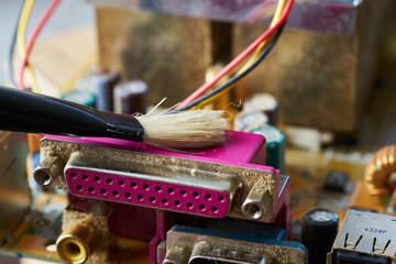 Brush cleaning an old computer board from dust and dirt. Close-up.