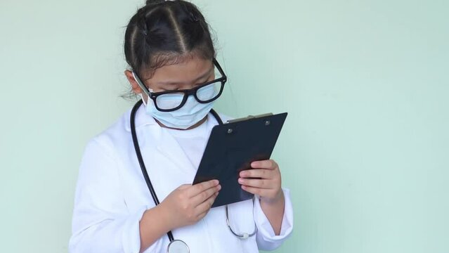 Little Kid Girl Asia In Black Glasses Is Playing A Doctor Checking In Clipboard And Thinking Expressions And Good Idea In Hospital Room