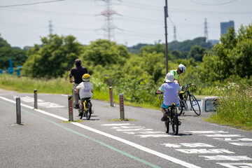 Obraz premium 初夏の休日、親子連れのサイクリング（手賀沼のサイクリングロード）