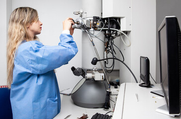 Young female scientist loading a specimen using a sample holder into a transmission electron microscope