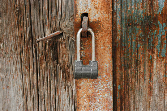 Old padlock on gates. A lock hangs on the wooden door