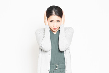 騒音に困って耳を塞いでいる女性