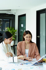 two asian businesswoman using documents to analyze jobs.