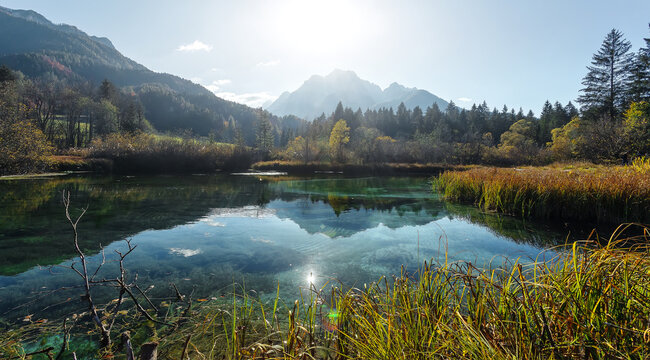 Awesome Alpine Valley at sunny day with majestic mountain peak on background. Scenic image of nature at lake Zelenci in autumn. Zelenci nature reserve. Triglav national park. Kranjska Gora, Slovenia.