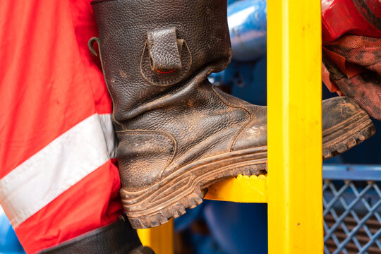Action of a construction worker is climbing on the platform ladder. An industrial working with unsafe action scene photo, close-up at the safety shoe.