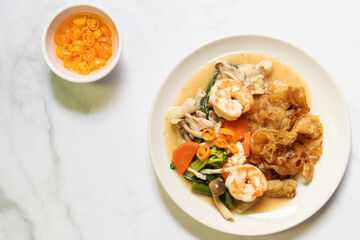 Fried noodles with shrimp and vegetable in gravy sauce with pickled chili in vinegar. Top view on white table background.