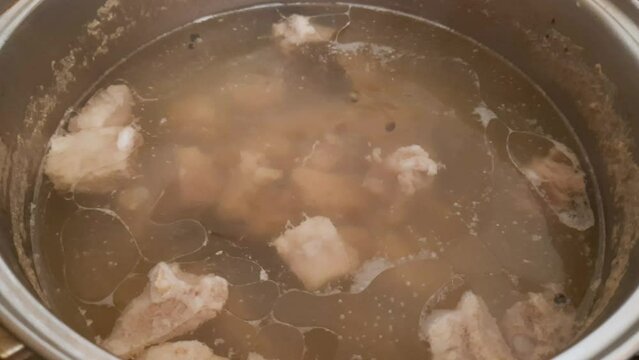 Meat broth during cooking in pot on a stove top