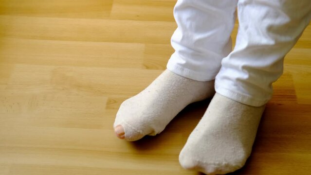 close-up of female feet on the floor in gray light cotton socks , the concept of women's health, an unpleasant event at a party, poverty, a sudden embarrassment