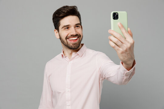 Young fun caucasian man 20s he wearing basic white shirt doing selfie shot on mobile cell phone post photo on social network isolated on plain grey background studio portrait People lifestyle concept