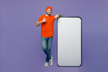 Full body young man wear red hat t-shirt big huge blank screen mobile cell phone workspace mockup area show thumb up isolated on plain pastel light purple background . Tattoo translates life is fight.