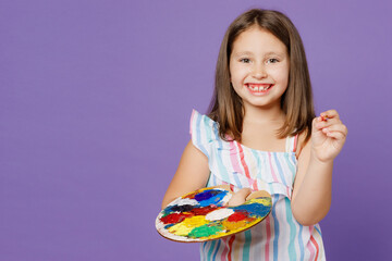 Little cheerful happy cute kid child girl 5-6 years old wears striped dress hold paint palette look...