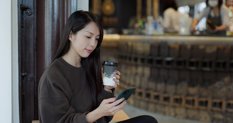 Woman enjoy her coffee with her phone in cafe