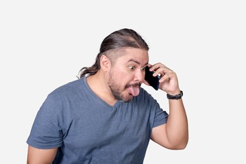 A man teases and ridicules someone over the phone. Sticking out his tongue out of habit....