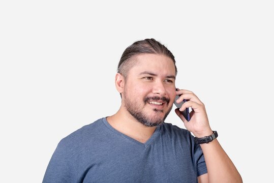 A man in his 30s and in a gray v-neck shirt talking to a friend or business acquaintance on his cellphone. Isolated on a white background. Communication concept.