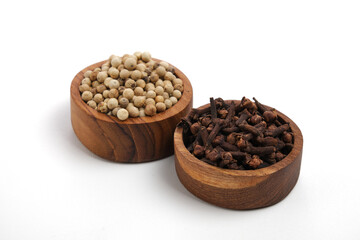 White pepper and cloves on wooden saucer white background