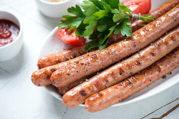 Close-up of grilled sausages with fresh parsley, tomatoes and dips, selective focus, studio shot