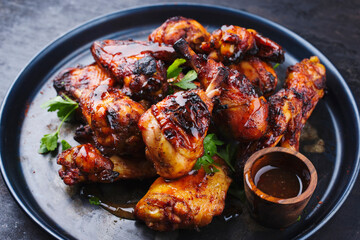 Traditionelle Hähnchenflügel und Keulen vom Grill mit scharfer Chili Mango Sauce und Koriander serviert als close-up auf einem rustikalen Board