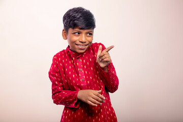 Boy wearing a traditional dress and  pointing away 