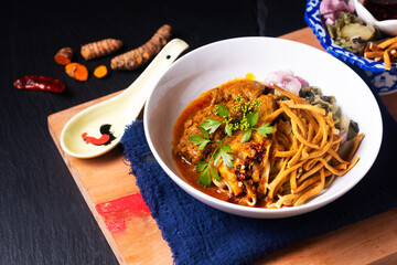 Thai Food concept Khao soi or Khao soy thai curry beef with egg noodles on wooden board on black background with copy space
