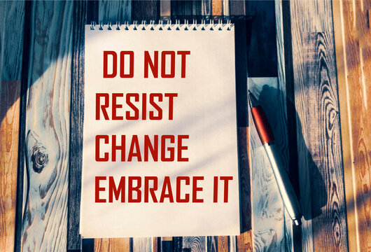 do not resist change, embrace it - motivational phrase on notepad with pen and vintage background