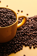Cup of freshly brewed roasted coffee beans on yellow background