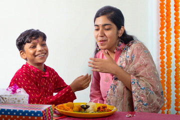 Brother feeding ladoos to his sister on the occasion of Raksha Bandhan