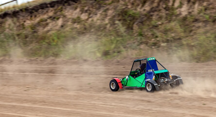 A small sports buggy with a child driving on a rally competition track during weekend training on a warm summer day.