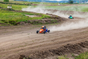 A small sports buggy with a child driving on a rally competition track during weekend training on a warm summer day.