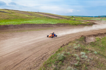 A small sports buggy with a child driving on a rally competition track during weekend training on a warm summer day.