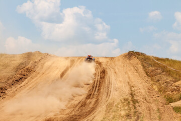 A sports buggy with a driver on a rally competition track during weekend training on a warm summer day. Fast driving with dirt from the wheels.