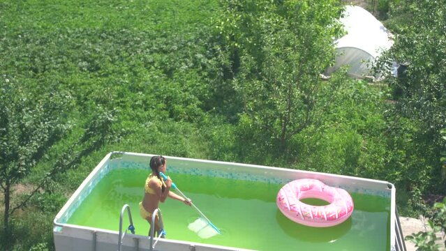 a little girl cleans a dirty swimming pool