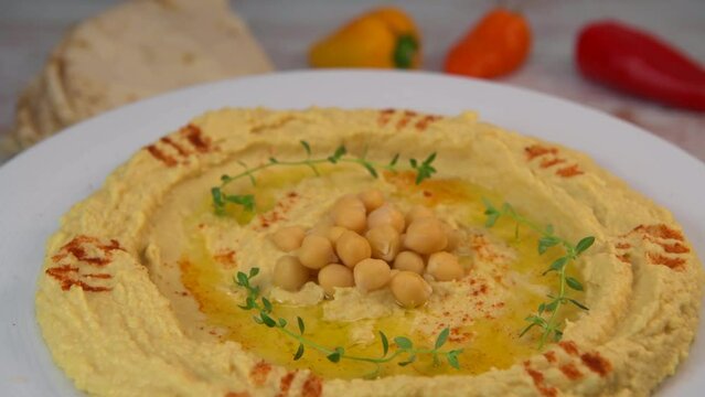 Homemade hummus with tahini plate with olive oil and paprika and pita isolated on brown background. High quality video 4k