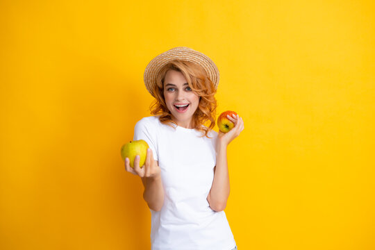 Young woman holding apples smiling with a happy and cool smile on face, showing teeth. Image of happy young pretty woman posing isolated over yellow background holding apple.