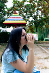 Woman drinking coffee in the park. Brunette woman at coffee break