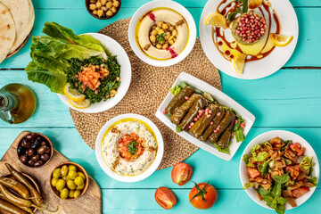Fototapeta na wymiar Assorted Arabian food Hommus Beiruti Meat, Baba Ghanouj , olive, chick peas, pita bread Vine Leaves, Tabbouleh, Fattoush, served in dish isolated on wooden table side view of middle eastern food