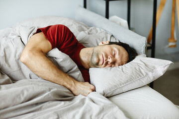Mature man lying on pillow under blanket and sleeping in his bed in bedroom